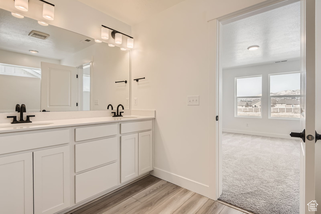 Bathroom with double vanity, baseboards, and wood finished floors