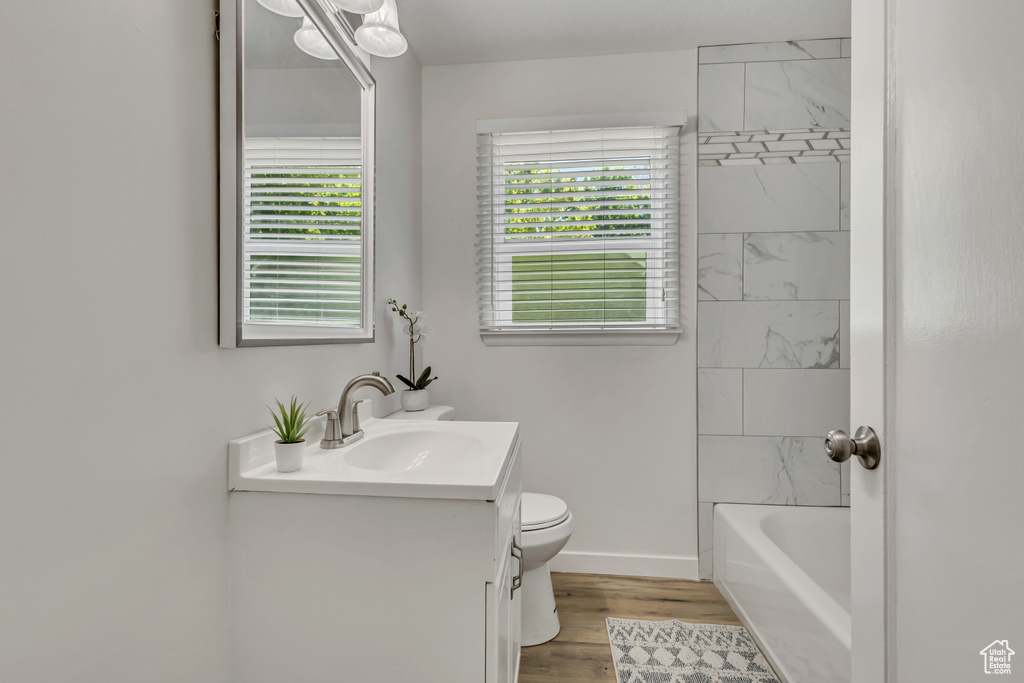 Full bathroom featuring toilet, vanity, baseboards, and wood finished floors