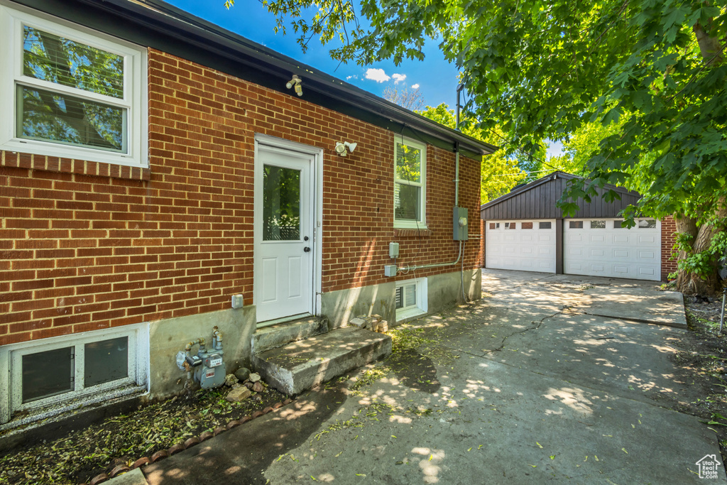 View of front of home featuring brick siding, an outdoor structure, a detached garage, and concrete driveway
