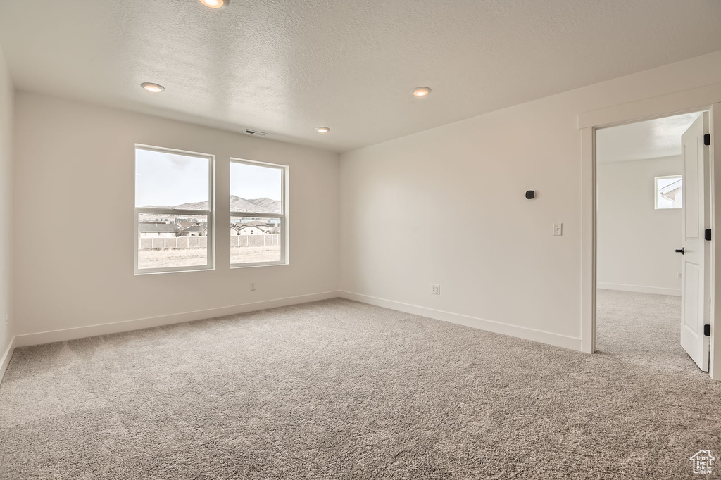 Carpeted empty room with baseboards and recessed lighting