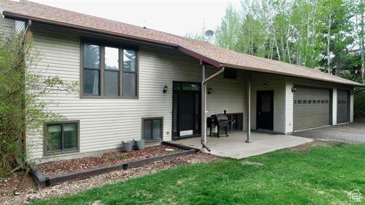 View of front of property with an attached garage, a patio area, driveway, and a front yard