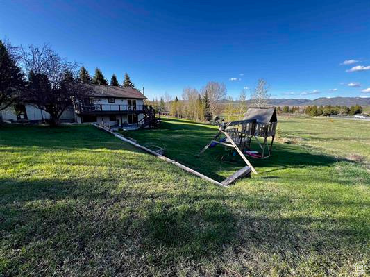 View of grassy yard featuring a playground and a wooden deck