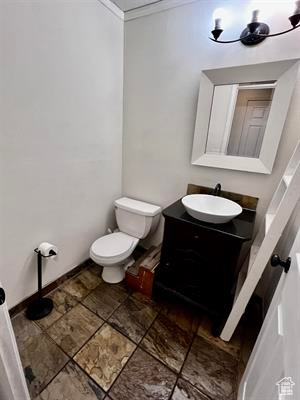 Half bath with crown molding, vanity, toilet, and baseboards