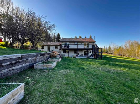 Rear view of property with a garden, stairway, a deck, and a yard