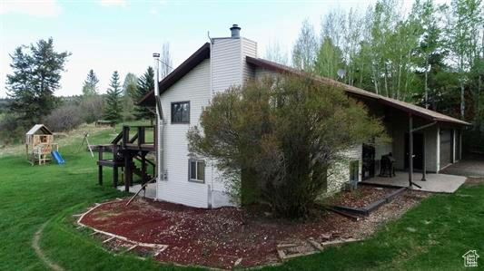 View of side of property featuring a patio area, a yard, a playground, and a chimney