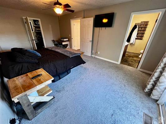 Bedroom with baseboards, carpet, ensuite bath, ceiling fan, and a textured ceiling