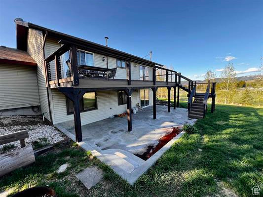 Rear view of house with a patio area, a lawn, stairs, and a deck