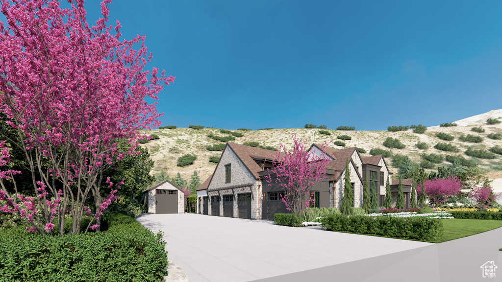 View of front facade featuring concrete driveway, stone siding, and a mountain view