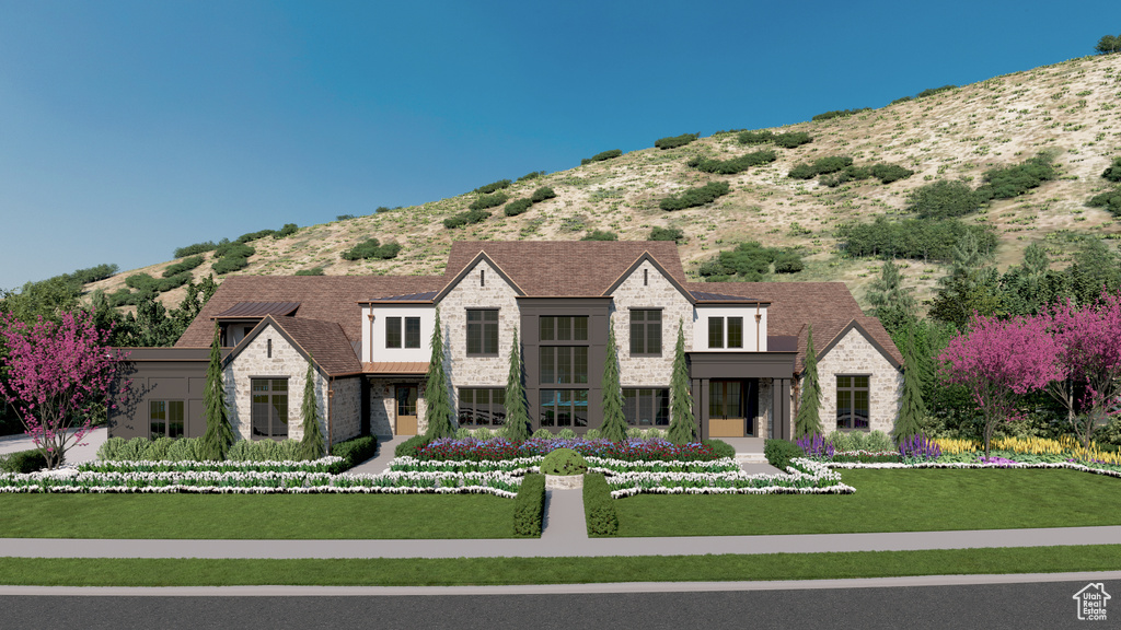 View of front of house with stone siding, a mountain view, and a front lawn