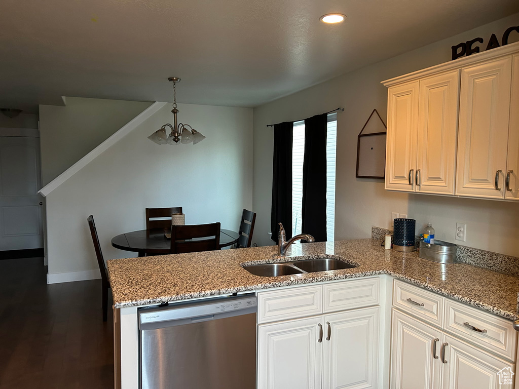 Kitchen featuring dishwasher, a sink, a peninsula, light stone counters, and decorative light fixtures