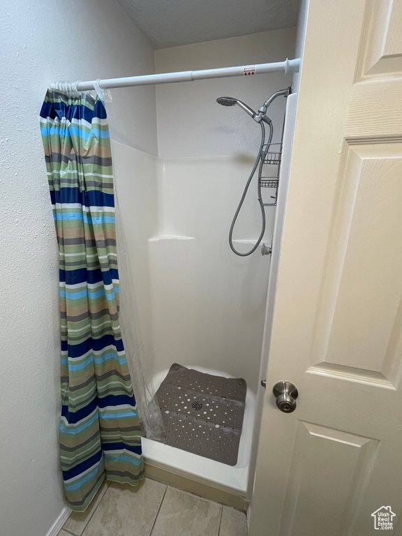 Full bath with a shower with curtain and tile patterned flooring