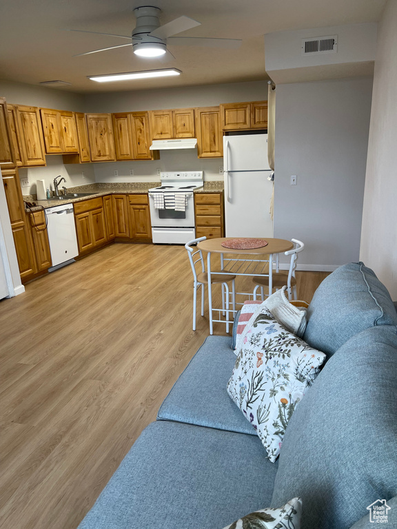 Kitchen with white appliances, under cabinet range hood, light wood-type flooring, ceiling fan, and brown cabinets