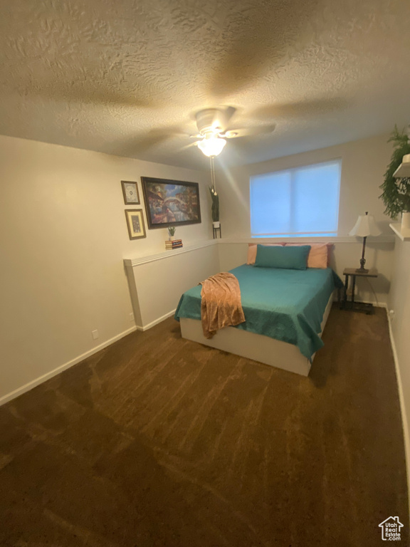 Bedroom featuring a textured ceiling, carpet floors, baseboards, and ceiling fan