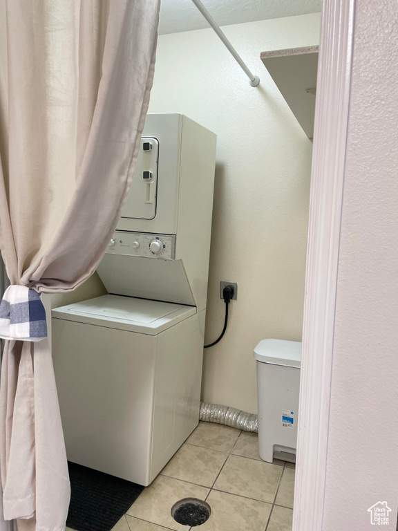 Washroom with stacked washer and clothes dryer and light tile patterned flooring