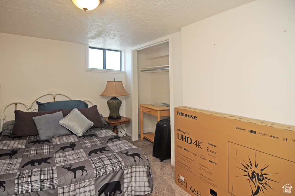 Bedroom with a textured ceiling, light carpet, and a closet