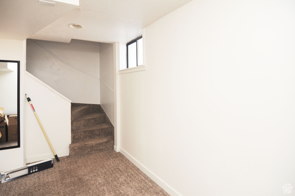 Below grade area with carpet floors, stairway, and baseboards