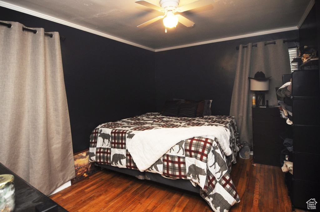 Bedroom featuring hardwood / wood-style flooring, ornamental molding, and ceiling fan