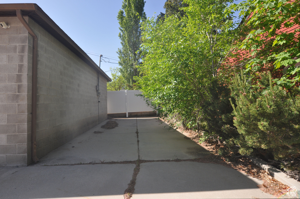 View of side of property with concrete block siding, fence, and a patio