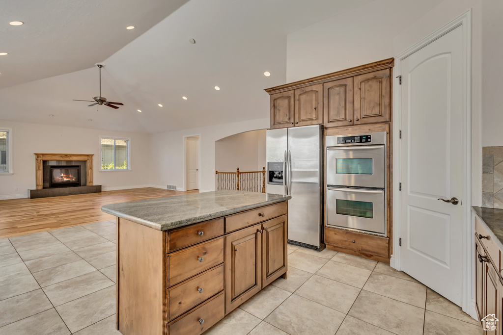 Kitchen featuring stainless steel appliances, a ceiling fan, light tile patterned floors, a glass covered fireplace, and recessed lighting