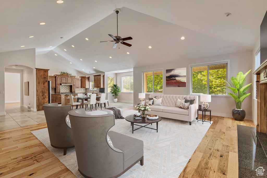 Living room with light wood-style flooring, arched walkways, plenty of natural light, recessed lighting, and high vaulted ceiling