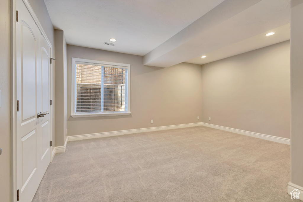 Spare room featuring light colored carpet, baseboards, and recessed lighting