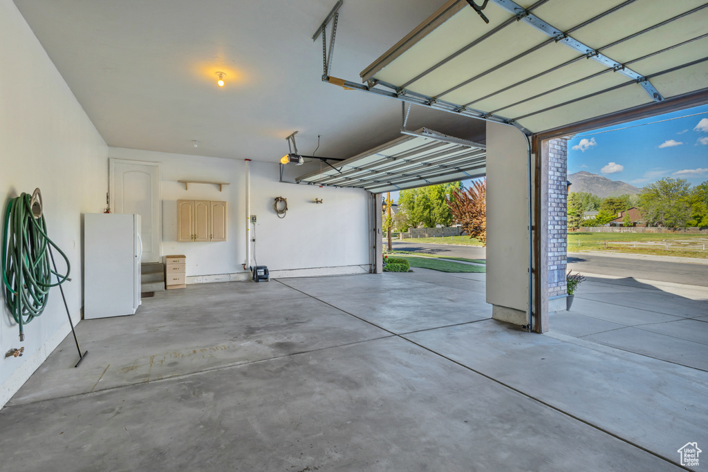 Garage with freestanding refrigerator, a mountain view, and a garage door opener