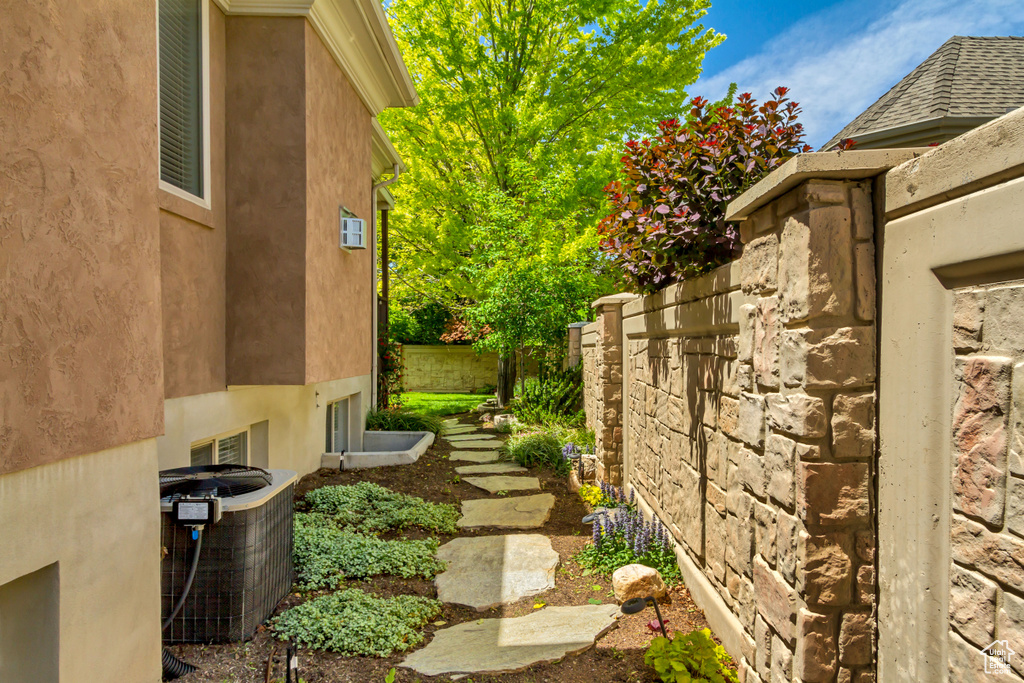 View of side of property with central AC unit, stucco siding, and fence