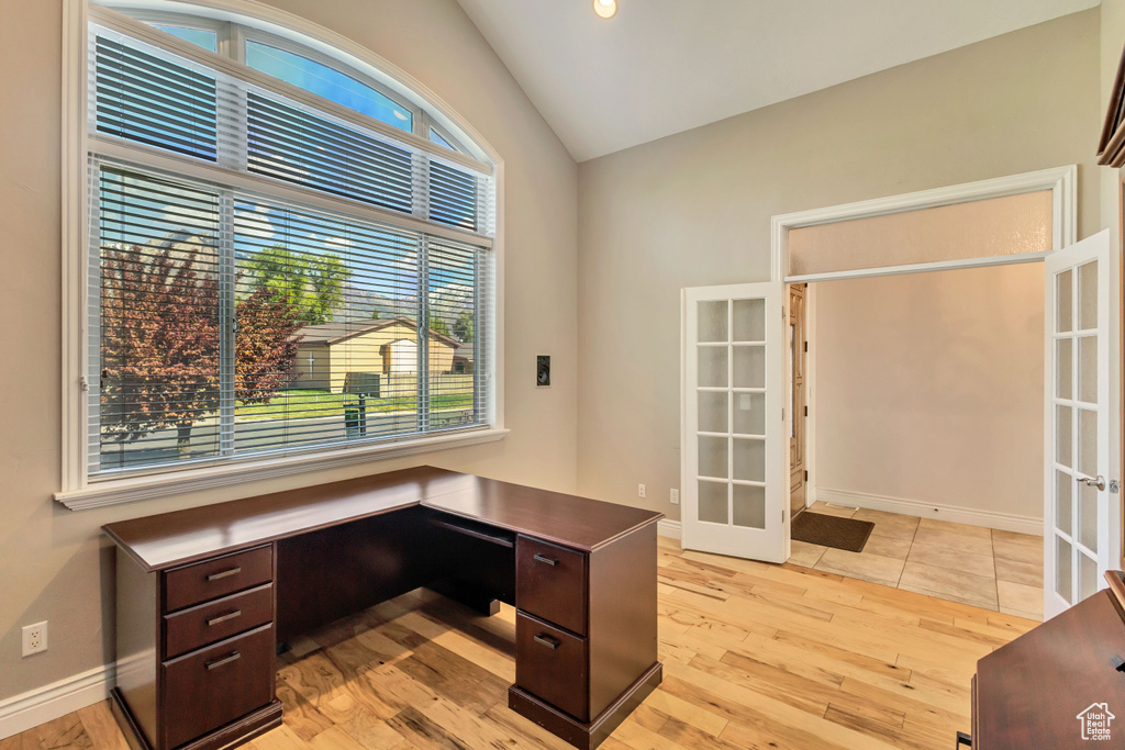 Unfurnished office with french doors, light wood-type flooring, vaulted ceiling, and baseboards