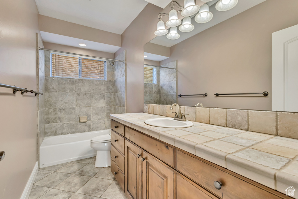 Bathroom with toilet, vanity, tile patterned flooring, bathing tub / shower combination, and baseboards