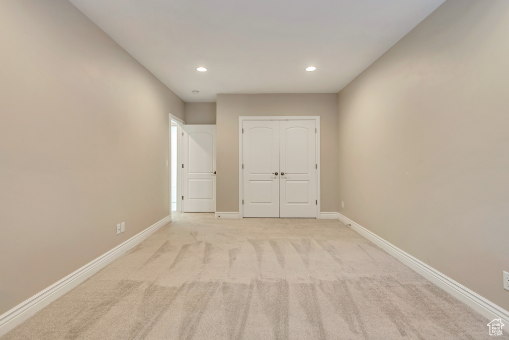 Unfurnished bedroom featuring recessed lighting, baseboards, a closet, and light colored carpet