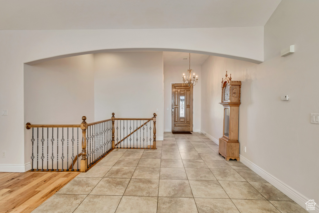 Foyer entrance featuring arched walkways, vaulted ceiling, a chandelier, baseboards, and light tile patterned flooring