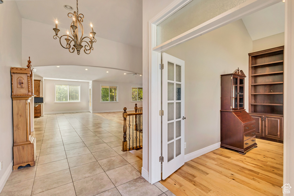 Foyer with a chandelier, high vaulted ceiling, baseboards, light tile patterned floors, and recessed lighting
