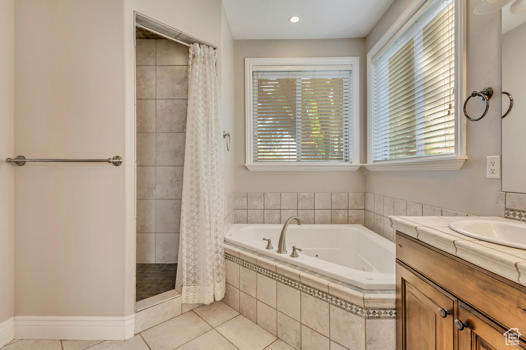 Bathroom featuring tile patterned floors, a tub with jets, a stall shower, and healthy amount of natural light