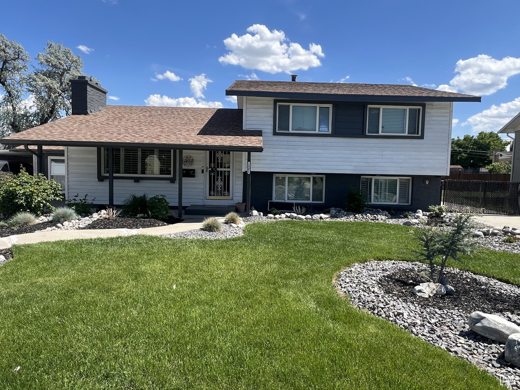 Split level home with a chimney and a shingled roof