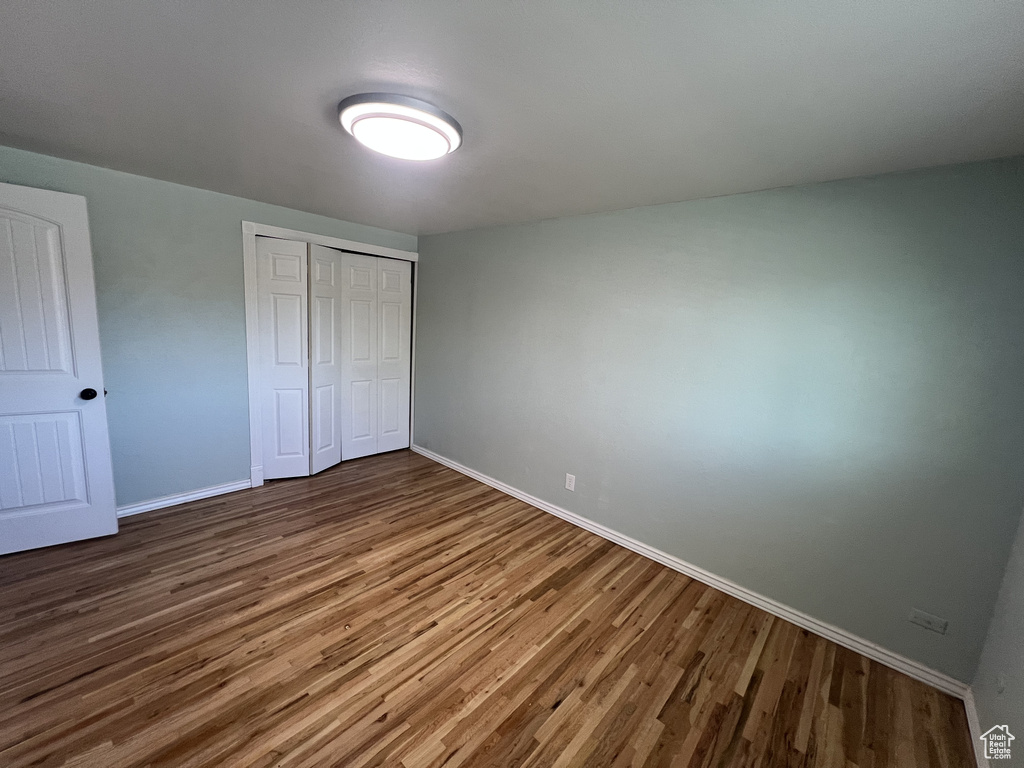 Unfurnished bedroom featuring wood finished floors, baseboards, and a closet