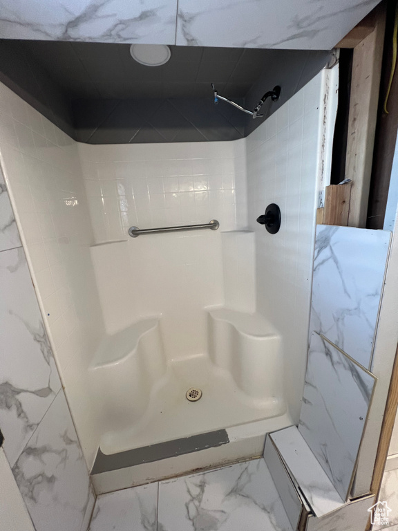 Full bathroom with marble look tiles and a shower