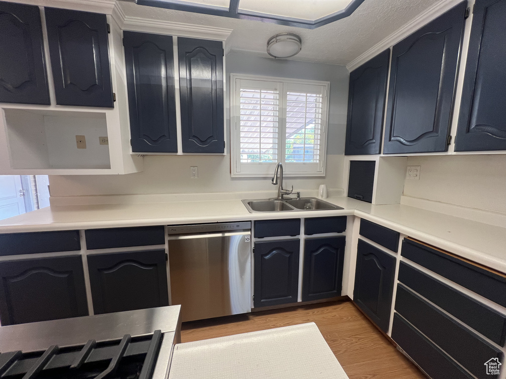 Kitchen with dishwasher, a sink, light wood-style flooring, light countertops, and blue cabinets