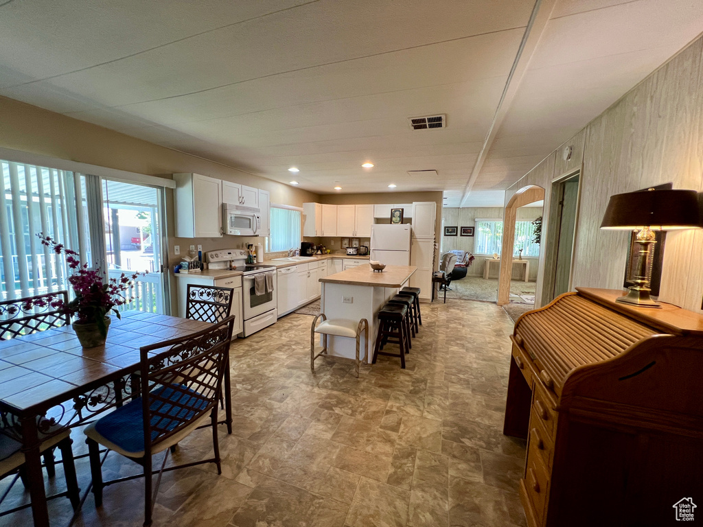 Dining room featuring arched walkways, healthy amount of natural light, stone finish flooring, and recessed lighting