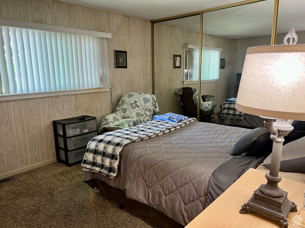 Carpeted bedroom featuring a closet and wooden walls