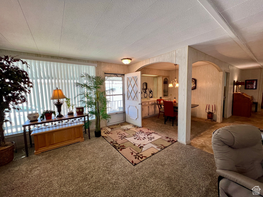 Entryway with arched walkways, wood walls, and light colored carpet