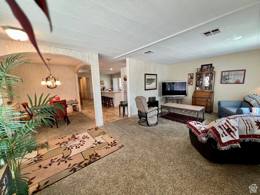 Living room featuring carpet, a chandelier, and arched walkways