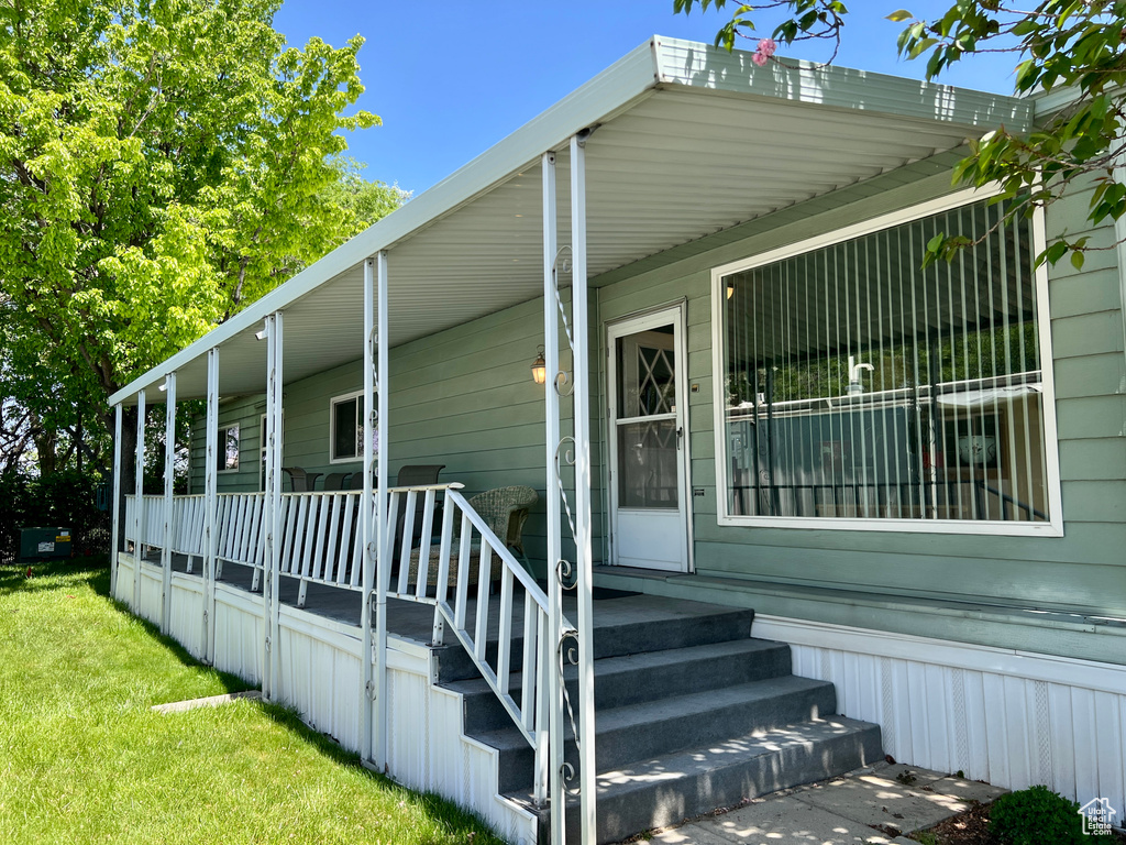 Entrance to property with covered porch and a lawn