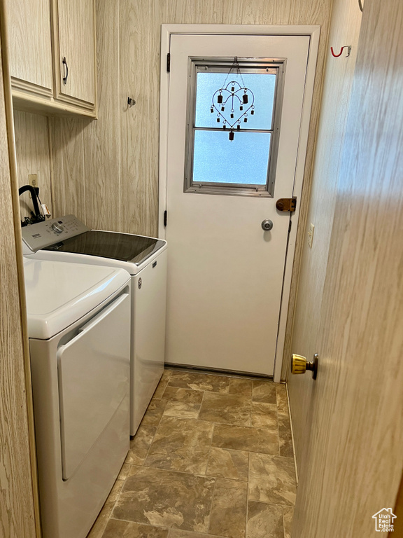 Washroom featuring cabinet space, washing machine and clothes dryer, and stone finish floors