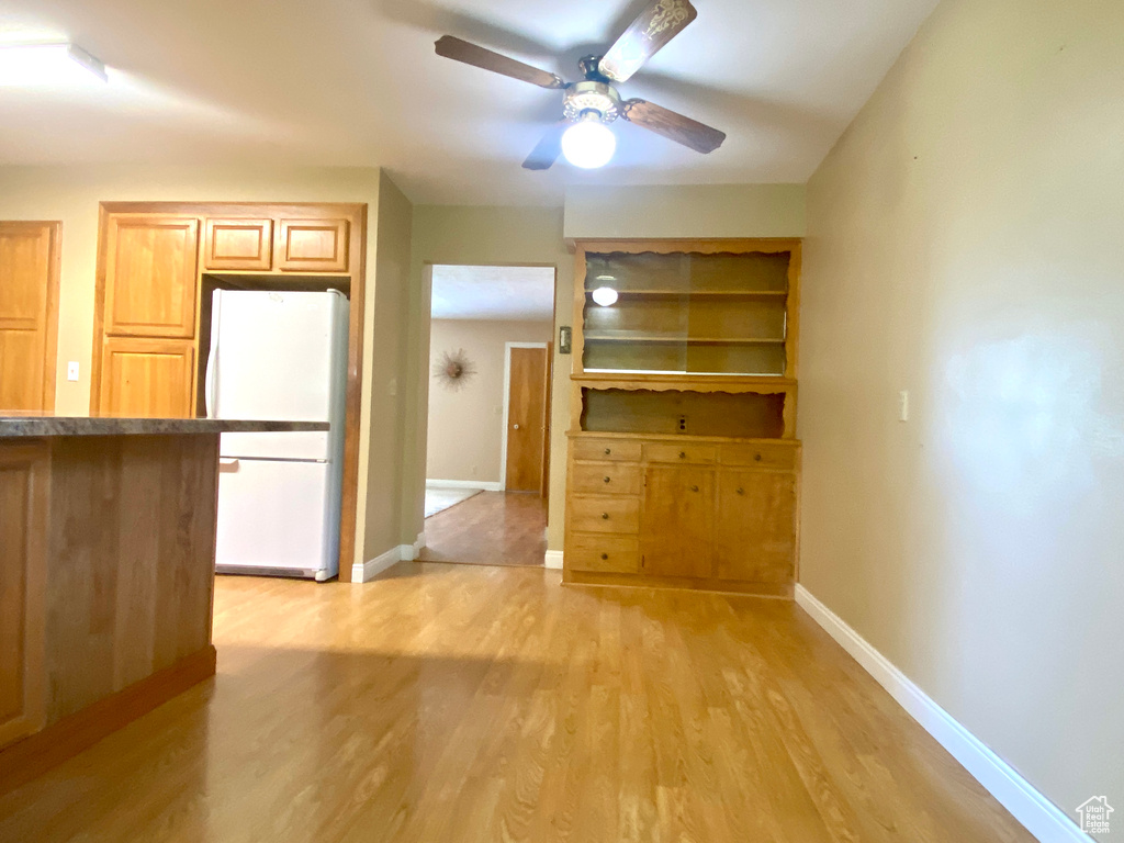 Kitchen featuring freestanding refrigerator, ceiling fan, light wood finished floors, and baseboards