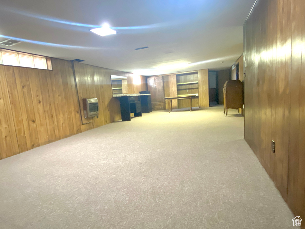 Below grade area with heating unit, wood walls, and carpet flooring