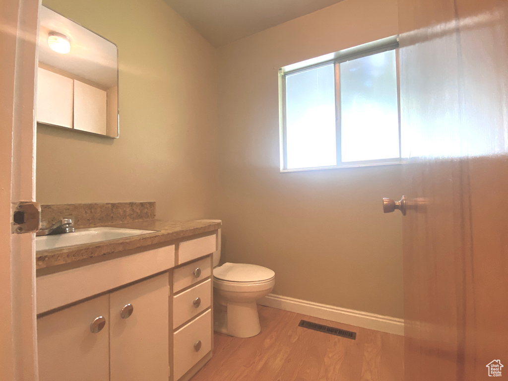 Bathroom featuring wood finished floors, toilet, vanity, and baseboards