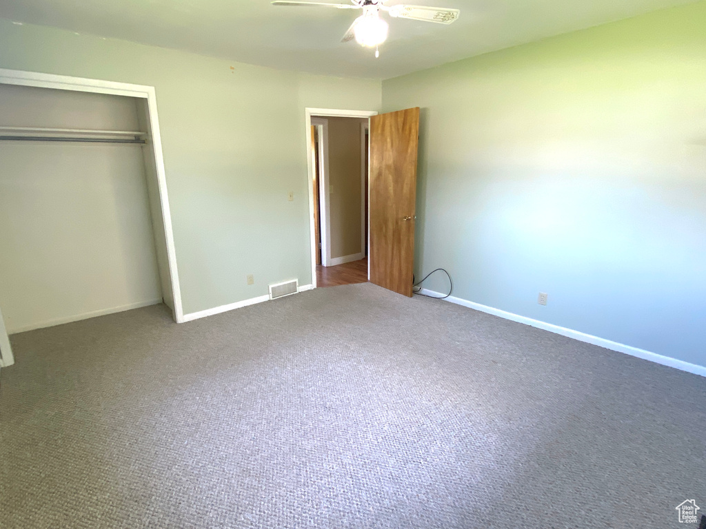 Unfurnished bedroom with a closet, carpet flooring, baseboards, and a ceiling fan