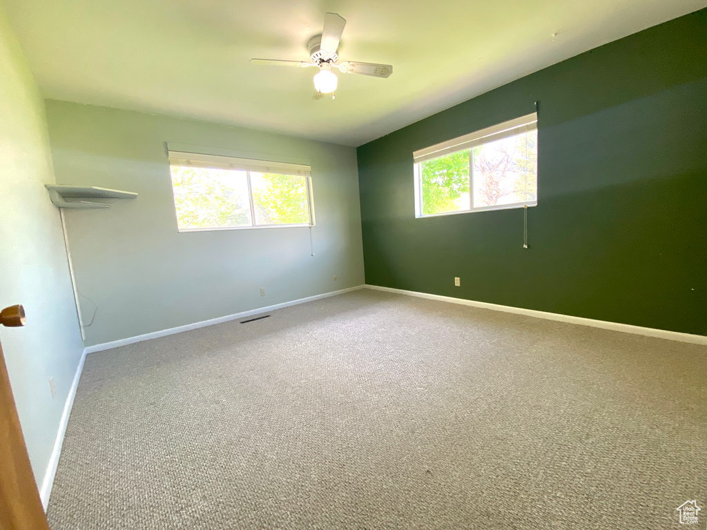 Unfurnished room featuring carpet, baseboards, and a ceiling fan