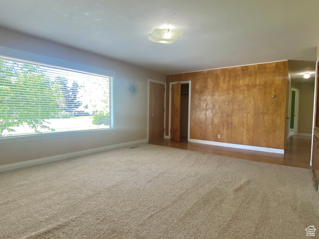 Spare room featuring carpet floors, baseboards, and wood walls