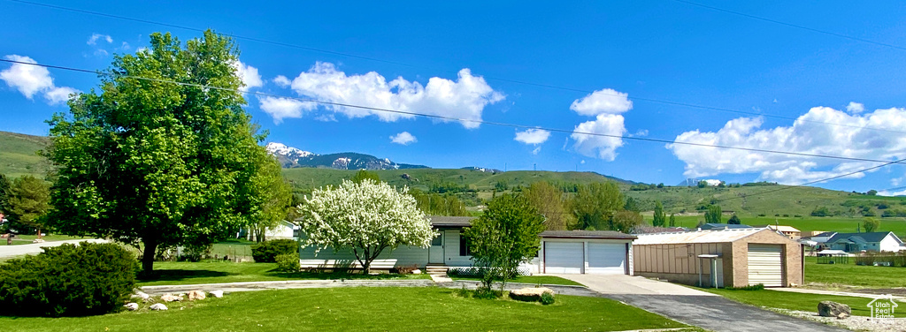 View of front facade featuring a front lawn, a mountain view, and a garage